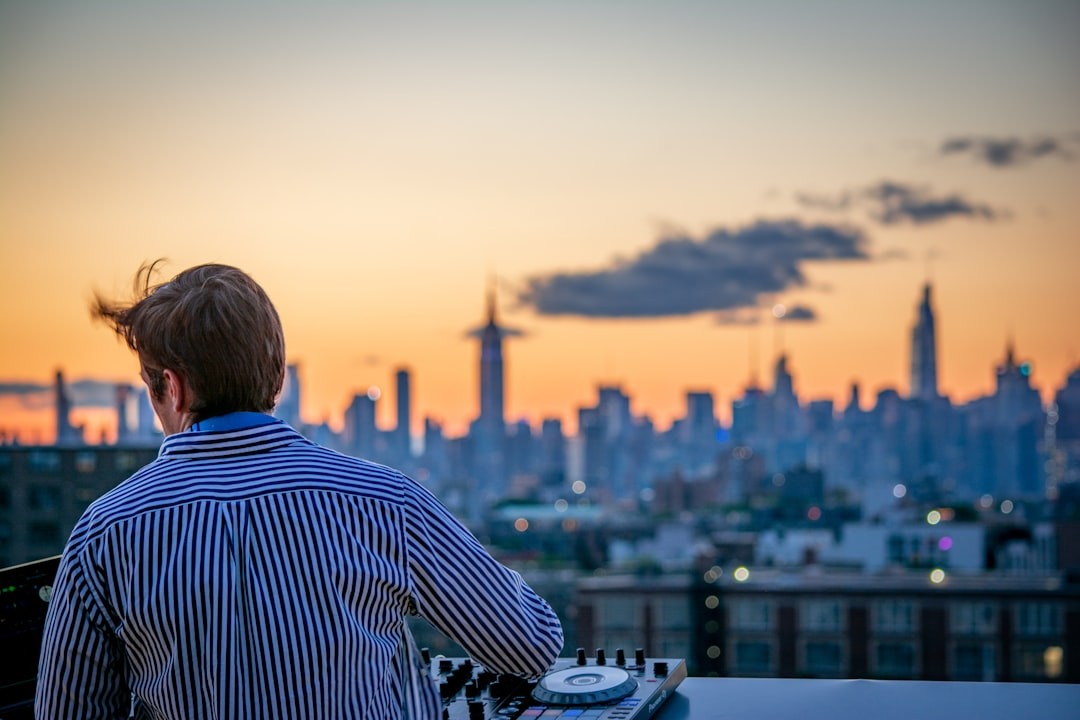 man in blue and white striped shirt looking at city skyline during daytime